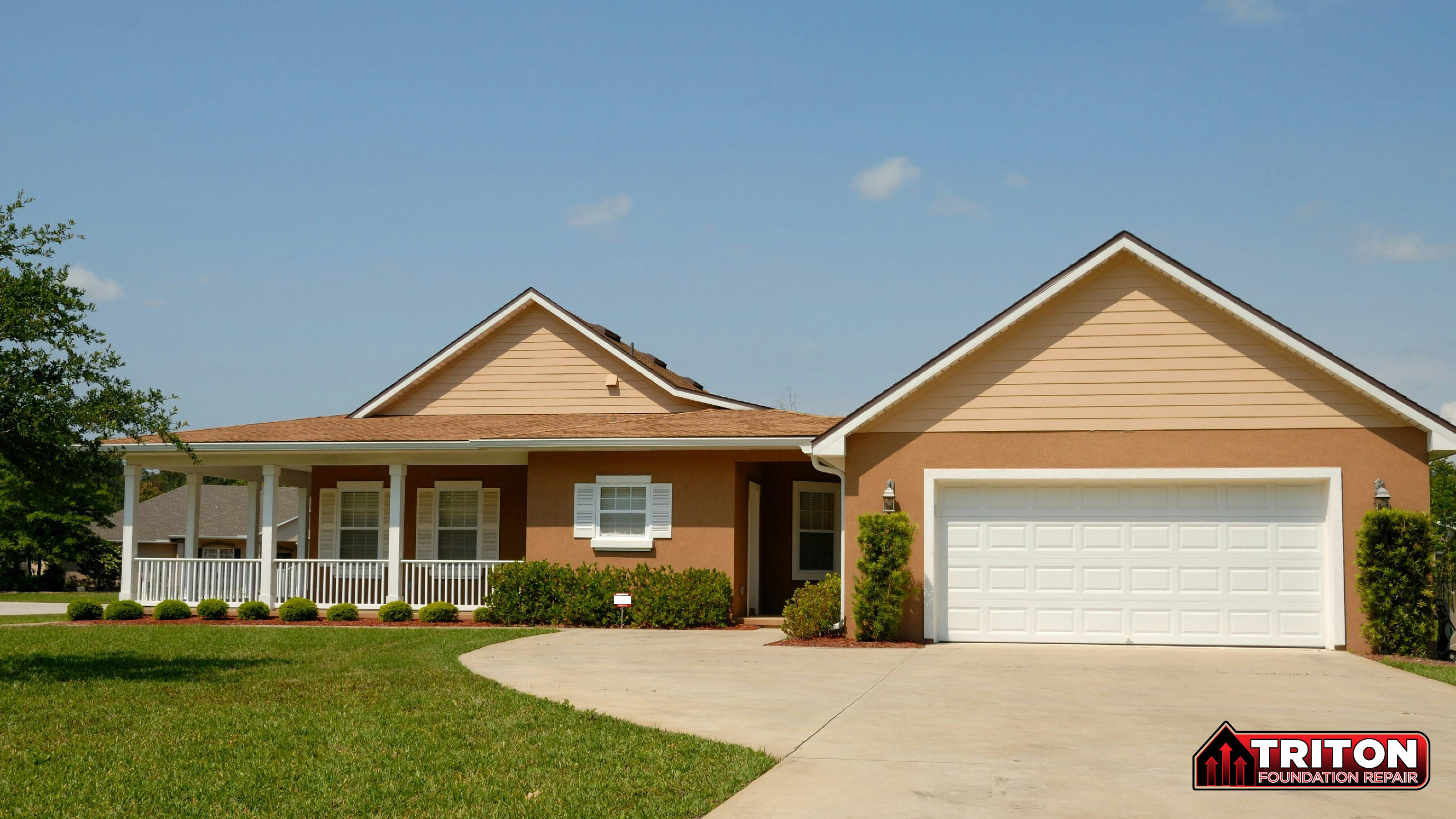 single-story suburban house with a beige exterior, white garage door, covered porch, and landscaped yard